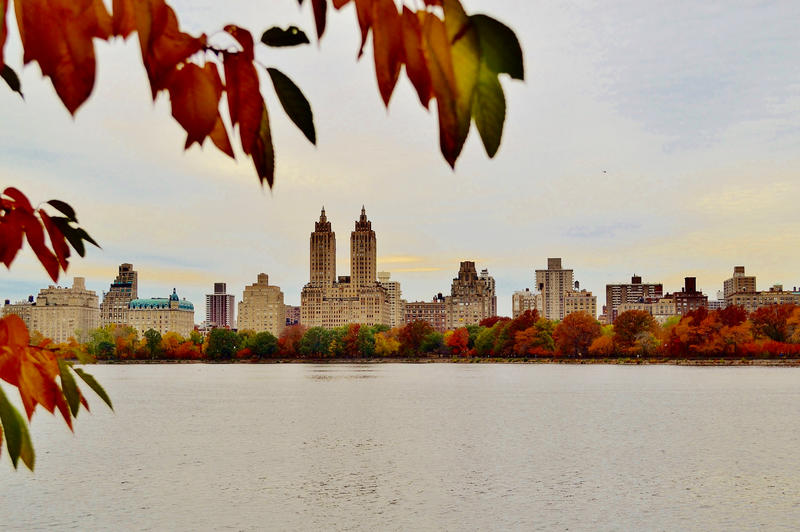The skyline of New York City set against deeply rich fall foliage along the Reservoir.