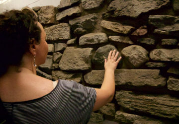 A tour guest touches an 18th century wall