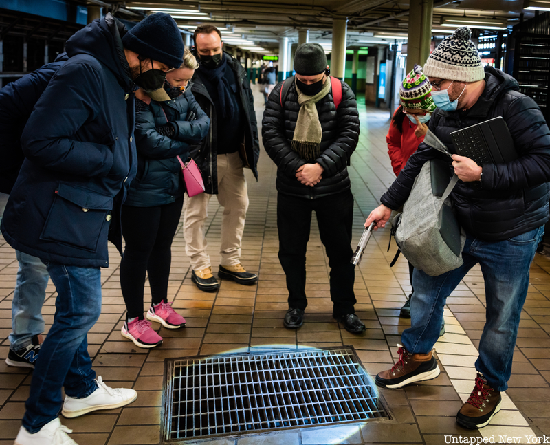 Tourgoers look into a subway grate