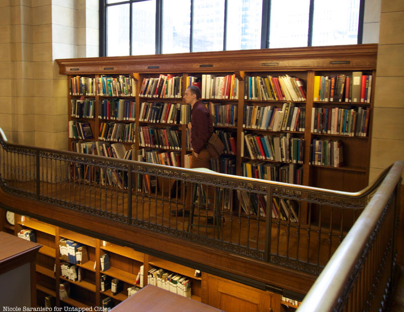 A person walks past stacks of books atop the Rose Reading Room catwalk at the New York Public Library