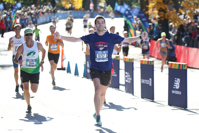 A happy runner spreads out his arms along the course of the NYC Marathon
