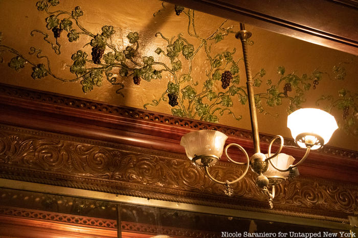 An intricate painted plaster grapevine detail on the ceiling behind the bar at Gage and Tollner