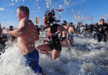 Swimmers run into the water at Coney Island for the New Year's Eve polar bear plunge