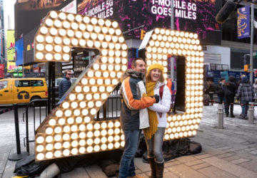 A couple poses in front of the 2 and 0 numerals for New Year's Eve in Times Square