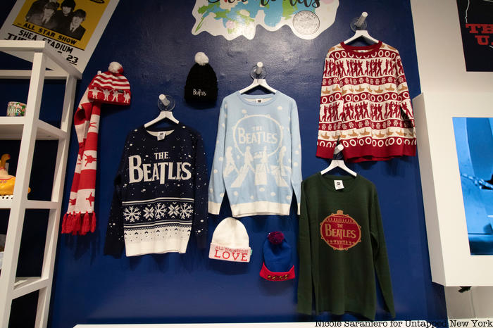 Beatles themed Christmas sweaters hang on a wall