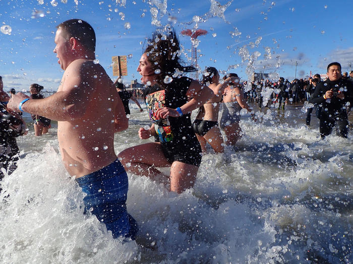 Swimmers run into the water at Coney Island for the New Year's Eve polar bear plunge