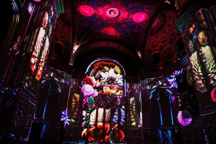Digital images of colorful flowers are projected onto the walls of the Cunard Building in the immersive show SuperReal