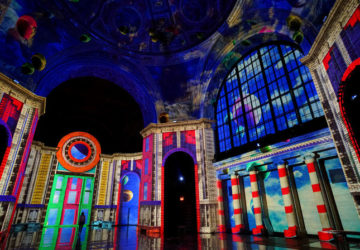 A rainbow colored image is projected onto the interior of the Cunard Building