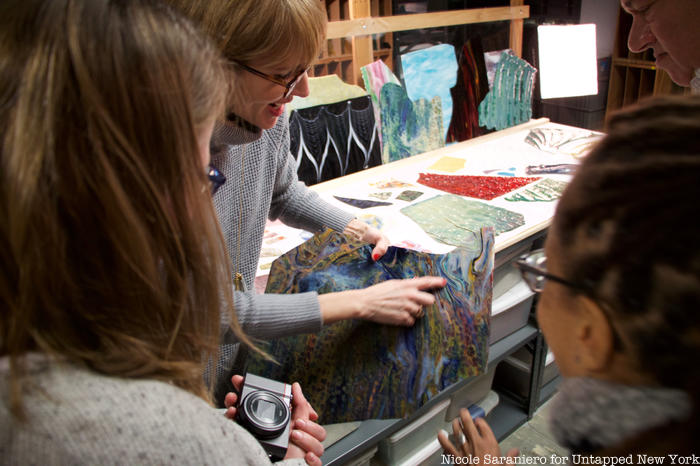 Tour guests examine a colorful piece of Tiffany glass