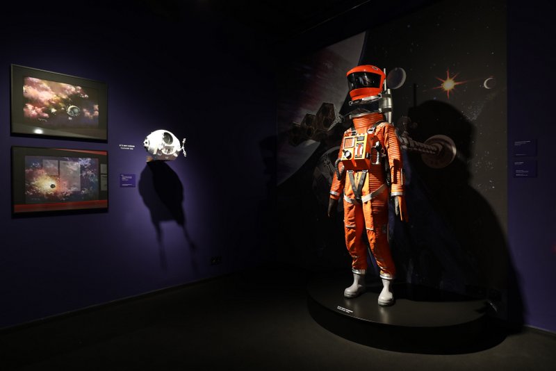 Prints of space and spacecrafts by concept artist Roy Carnon (left) and a space suit worn in the Clavius Base scene in 2001: A SPACE ODYSSEY, as presented in “Kubricks 2001: 50 Jahre A Space Odyssey” exhibition at the DFF – Deutsches Filminstitut & Filmmuseum in Frankfurt am Main (2018). Credit: Photo credit: DFF/© Sophie Schüler