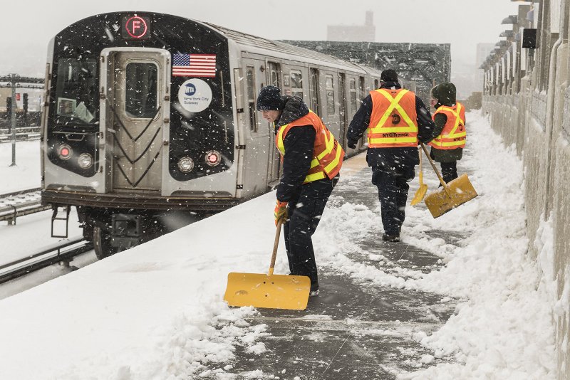 Workers clearing snow from F train platform