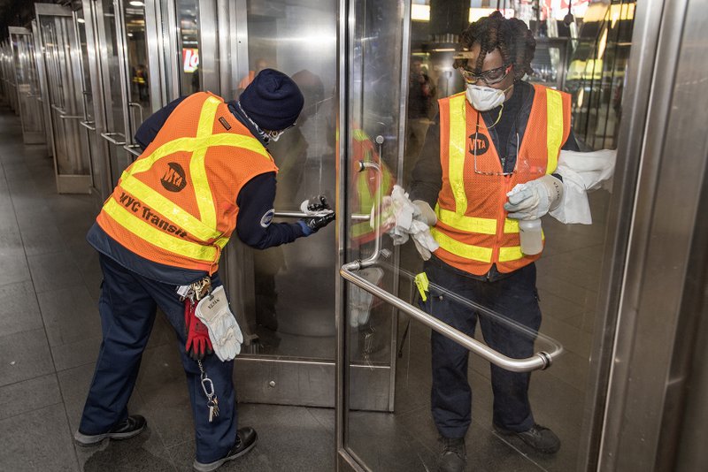 MTA workers disinfecting doors in subway