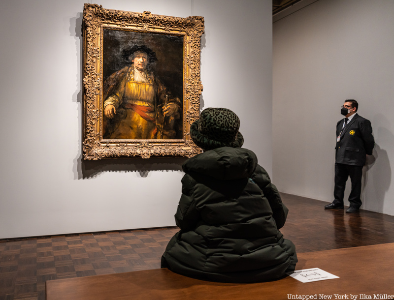 Woman on bench looking at Rembrandt painting at Frick Madison