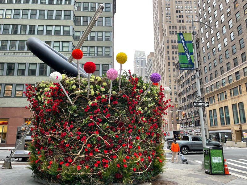 Giant Pin Cushion art installation on the street in the garment district created with colorful botanical materials