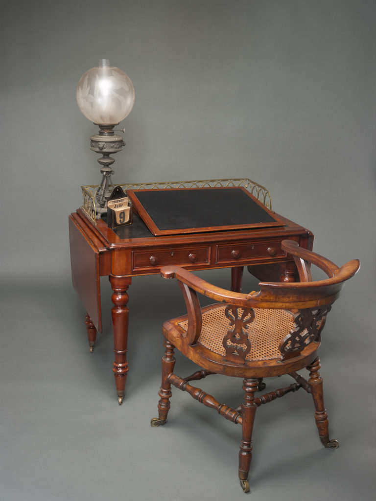 Charles Dickens's desk, writing slope, lamp, desk calendar, and chair in the Polonsky Exhibition. Photo by Robert Kato.