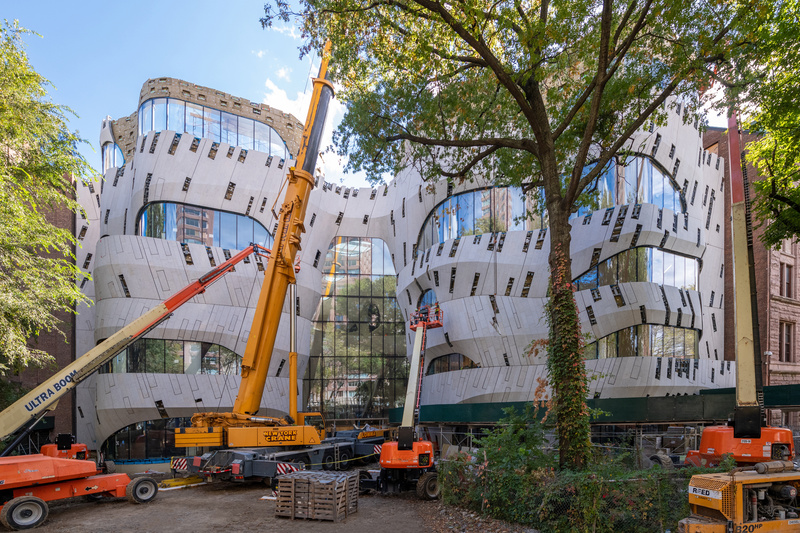Orange cranes are parked outside the entrance to the new Gilder Center at AMNH