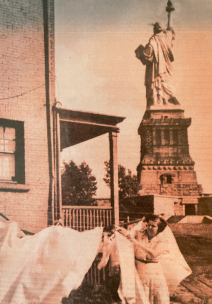 Carol's mother handing up laundry outside their house on Liberty Island
