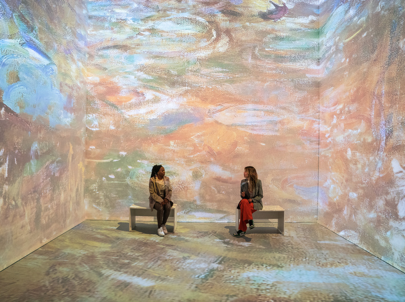 Two people sit on a bench at Monet's Garden Immersive Experience