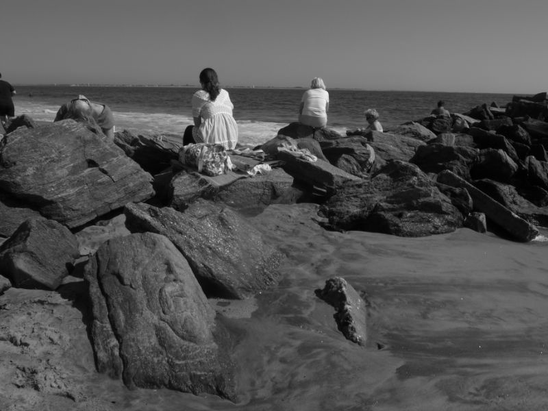 People sitting on rocks above Stone carvings at Brighton Beach