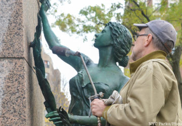 Man makes repairs to a bronze female sculpture