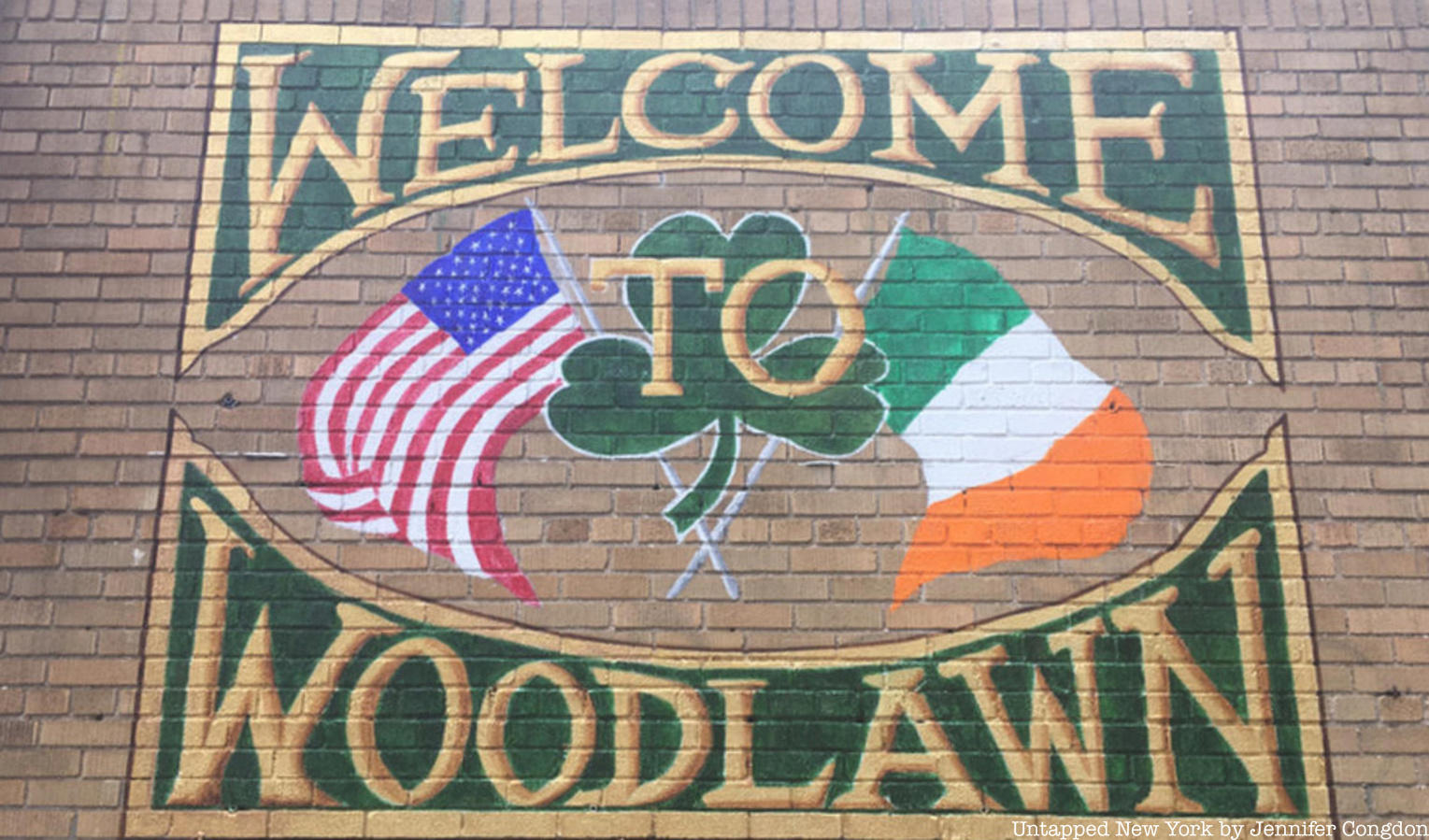 "Welcome to Woodlawn" painted sign on a brick wall with Irish and American flag