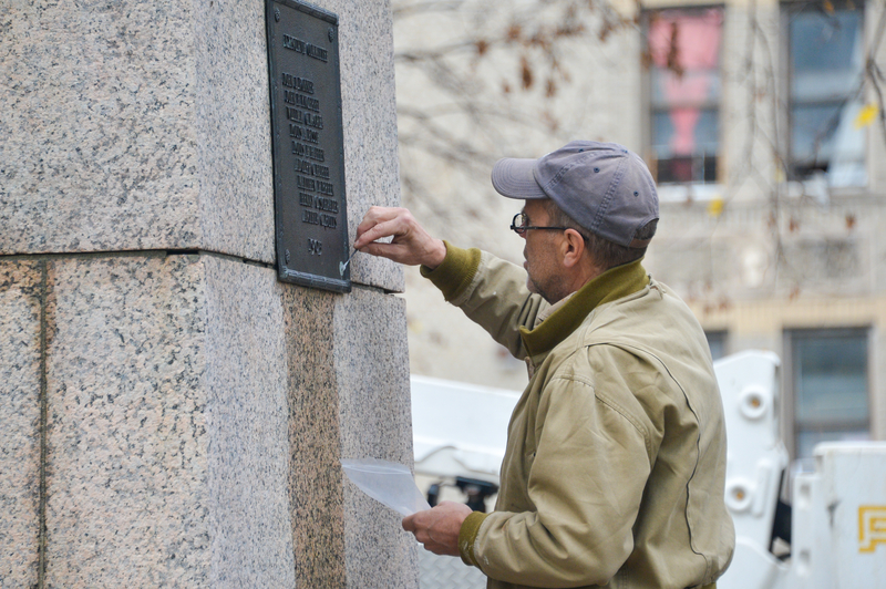 A man makes repairs to a plaque on the Heintz monument in the Bronx