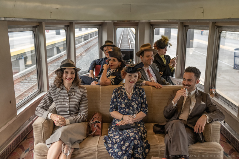 People dressed in vintage attire inside a vintage rail car