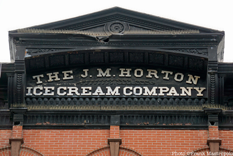 A ghost sign for J.M. Horton Ice cream in the black cornice of a brick building