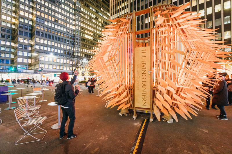 A person takes a photo of the Living Lantern art installation in the Garment District