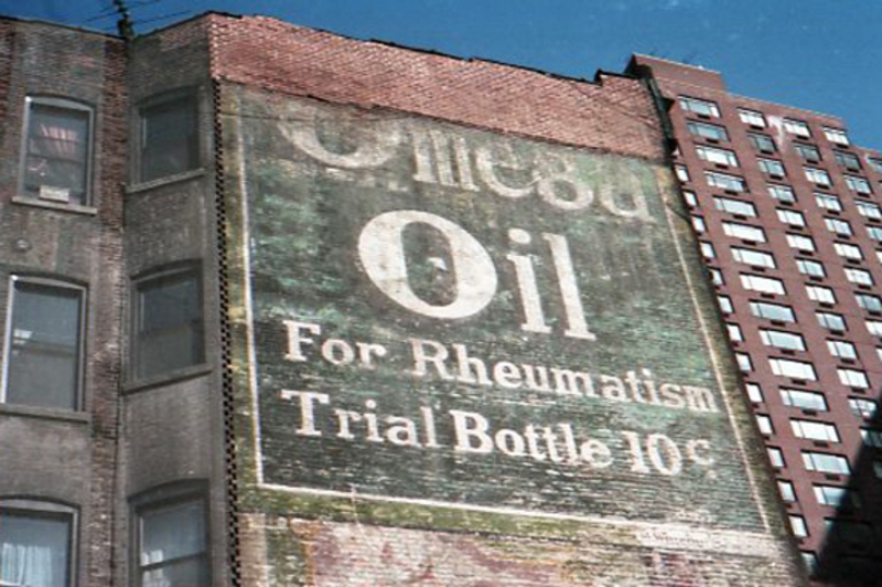 Ghost sign that says "Omega Oil for Rheumatism trial bottle 10 cents"