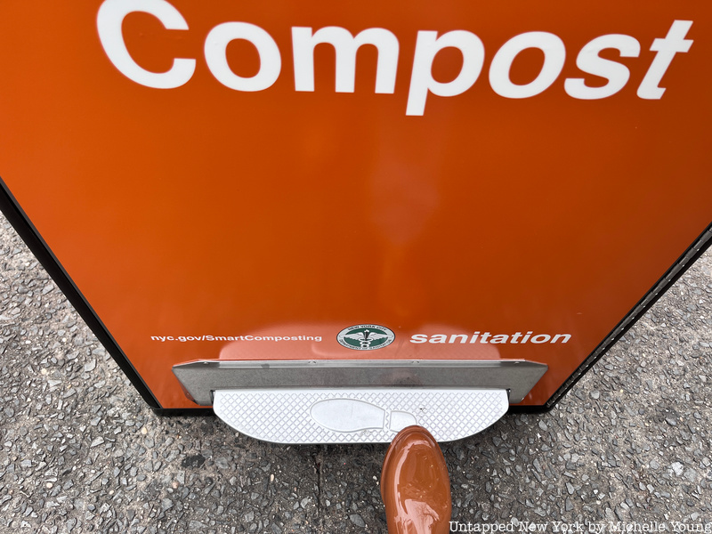 Metal foot pedal on orange smart compost bin in NYC