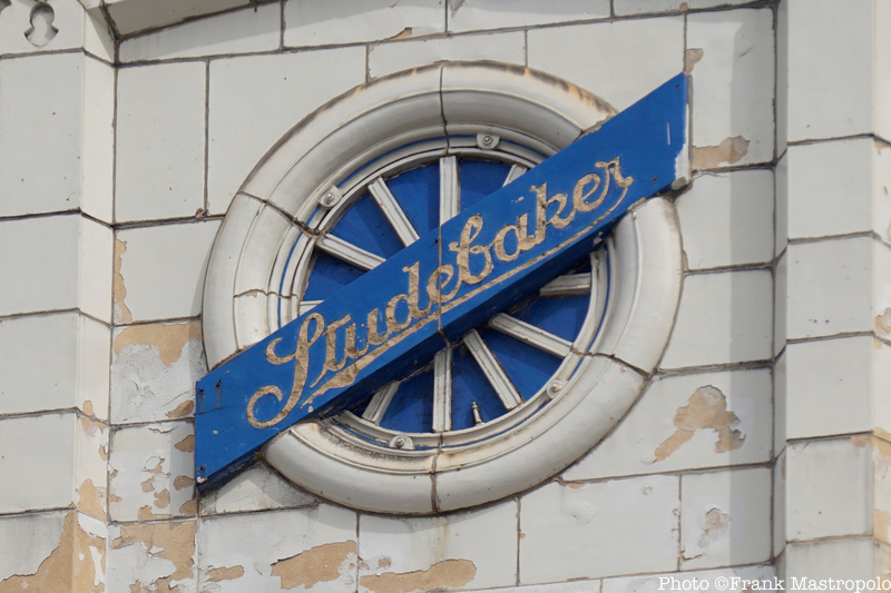 A blue banner shaped ghost sign that says Studebaker in peeling letters