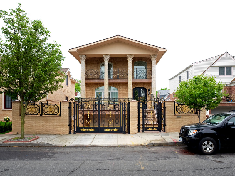 A large house in Rego Park Queens with a black and gold fence