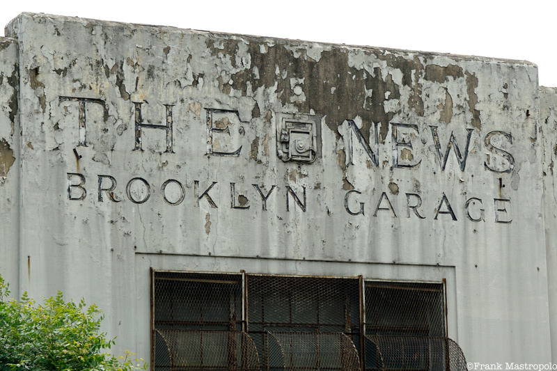 A ghost sign with peeling white paint at the top of the old Daily News garage building in Brooklyn