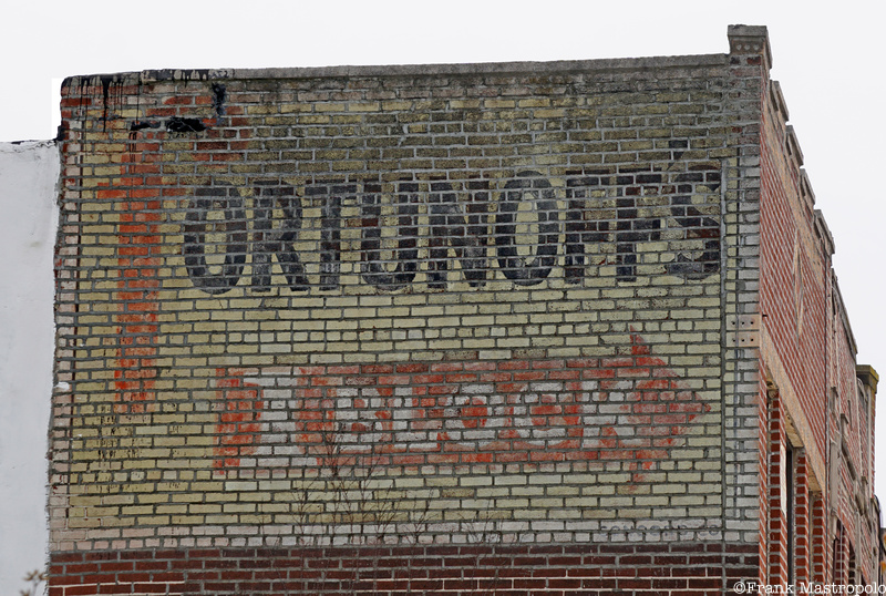A fading Brooklyn ghost sign on the side of a brick building that reads "Fortunoffs" with a red arrow that says "1 Block"