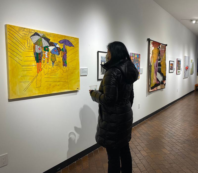 A woman looks at a wall of art at the heller Museum