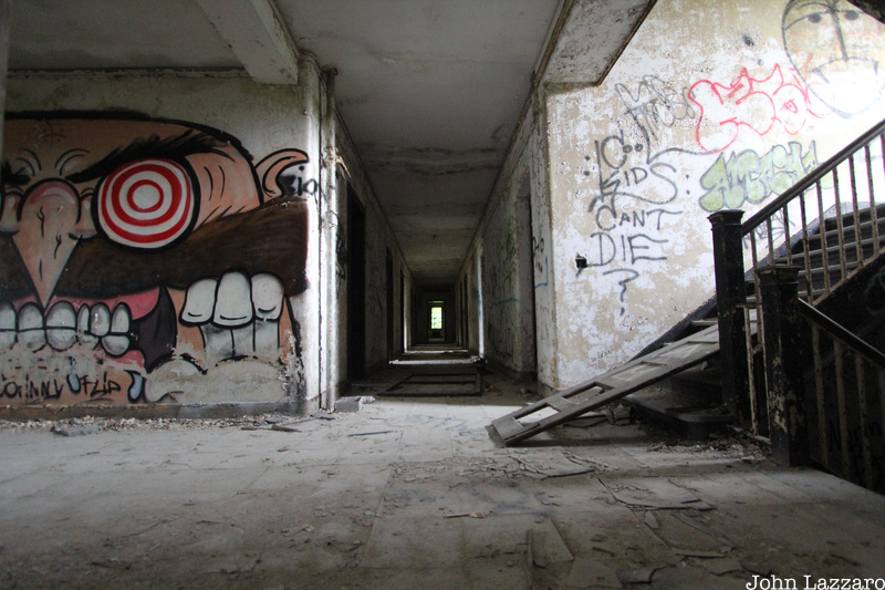 A large piece of graffiti art on a wall next to a staircase at the abandoned Kings Park Psychiatric