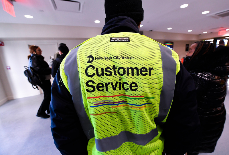 An MTA worker wearing a bright yellow vest that says "Customer Service"