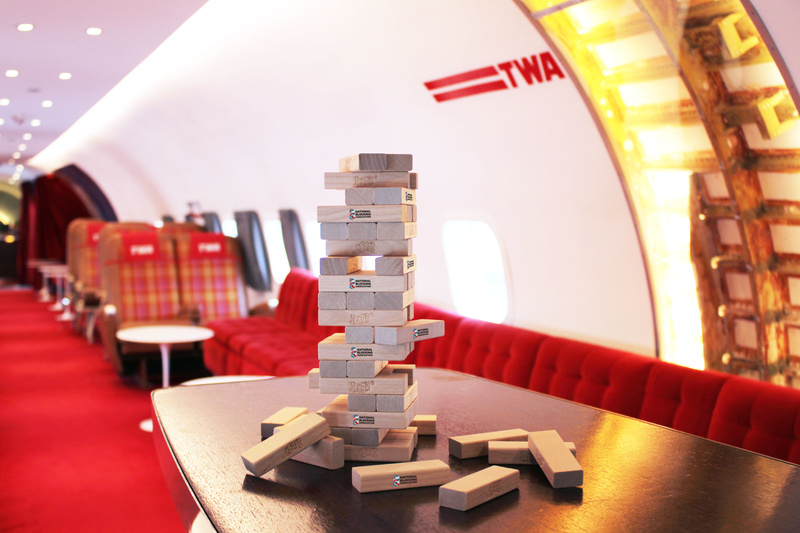 A stack of JENGA blocks on a. table inside the airplane bar at TWA Hotel