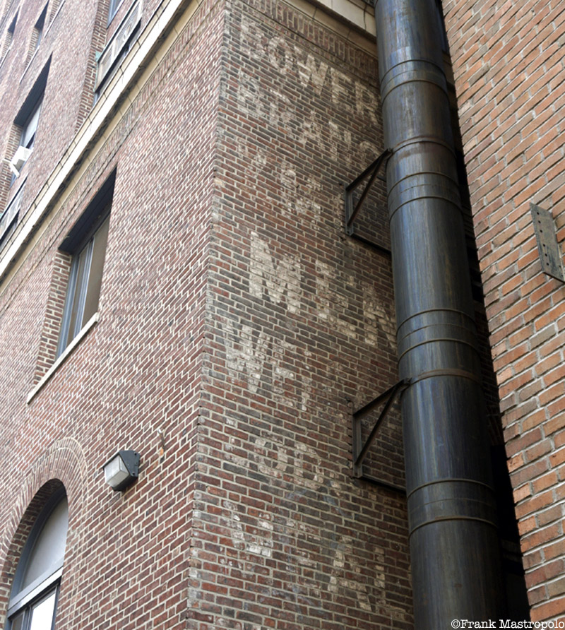 A faded, obscured ghost sign in the East Village reads, "Bowery Branch YMCA, Men Welcome, Lodging, Meals, Employment."