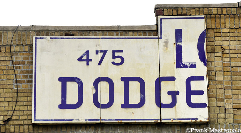 A severed ghost sign in Williamsburg, Brooklyn hangs over the former London Motors Dodge-Plymouth service center.