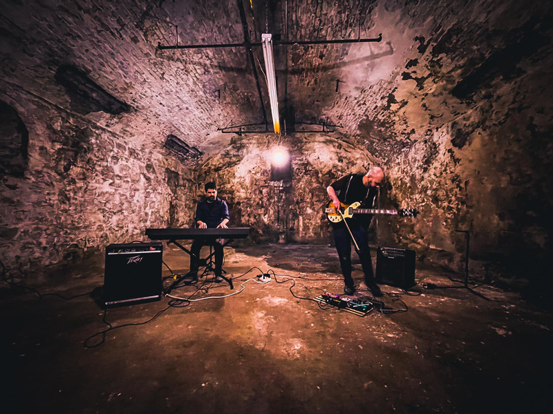 A guitar player and keyboardist inside a beer vault