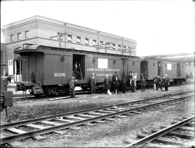Black and white photo of a group of men standing outside a train car