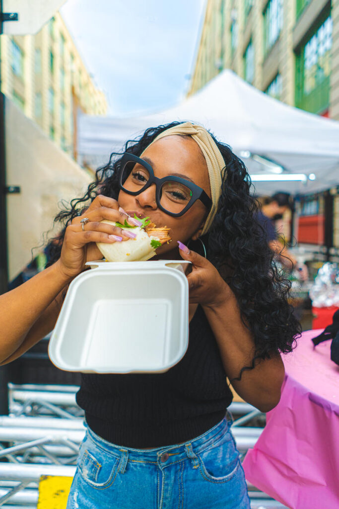 A women bites into food at the Brooklyn Night Market at Industry City