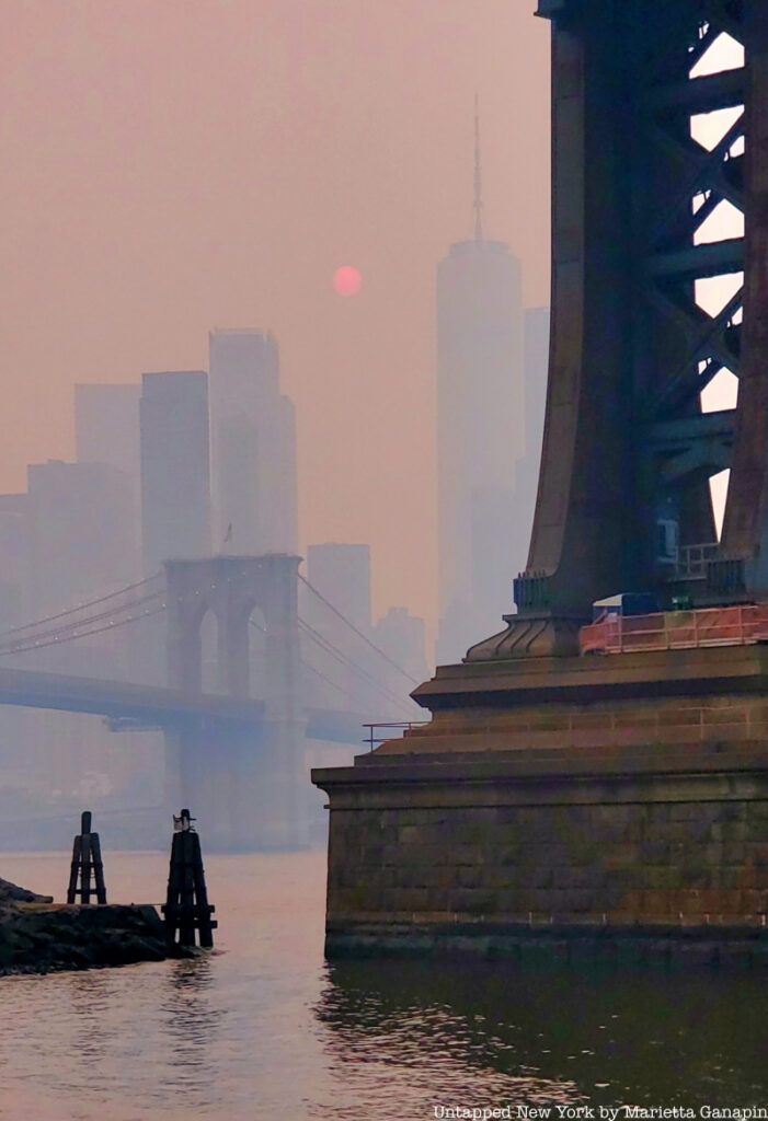 Manhattan Bridge and Brooklyn Bridge under hazy orange skies due to bad NYC air quality