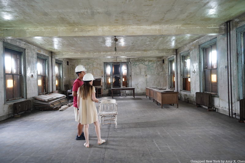 A couple stands in an empty room at the abandoned Ellis Island hospital