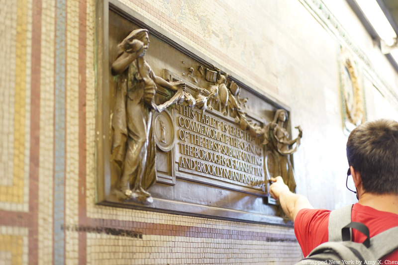 Tour guide points to a plaque in the Brooklyn Subway