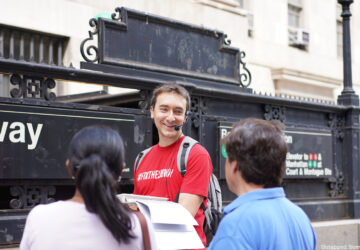 A tour guide addresses two guests at a subway entrance