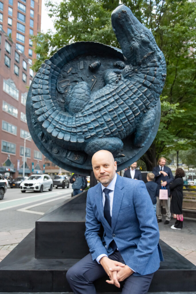 Alexander Klingspor, the artist, sits in front of his alligator sculpture