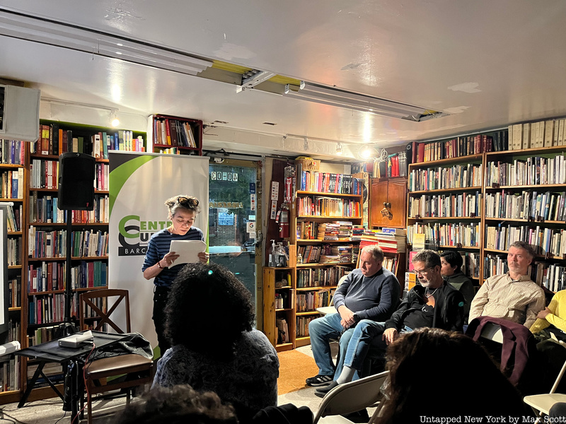 A woman stands in front of a small crowd inside Librería Barco de Papel bookstore in Queens